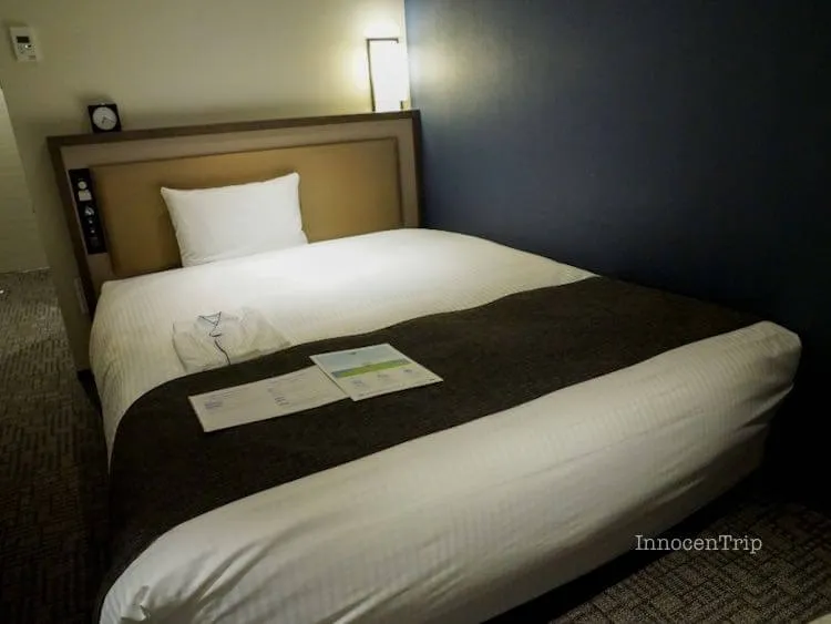 落ち着いた照明に包まれたダブルルームのベッドと枕