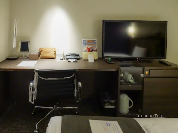 ワイドデスクと壁掛け風テレビが配置されたワークスペース