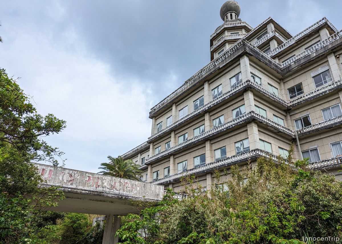 雨に濡れた道沿いにひっそり佇む廃業したホテルの建物