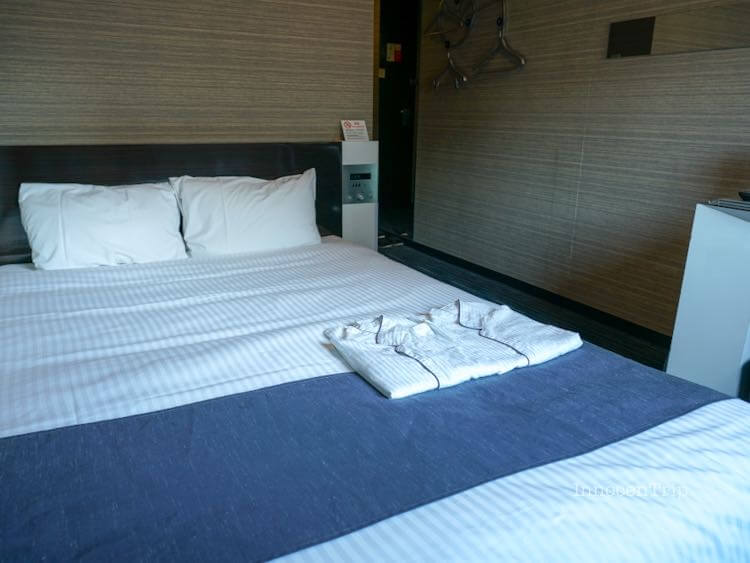 ダブルルームのベッドとシンプルなベッドサイド